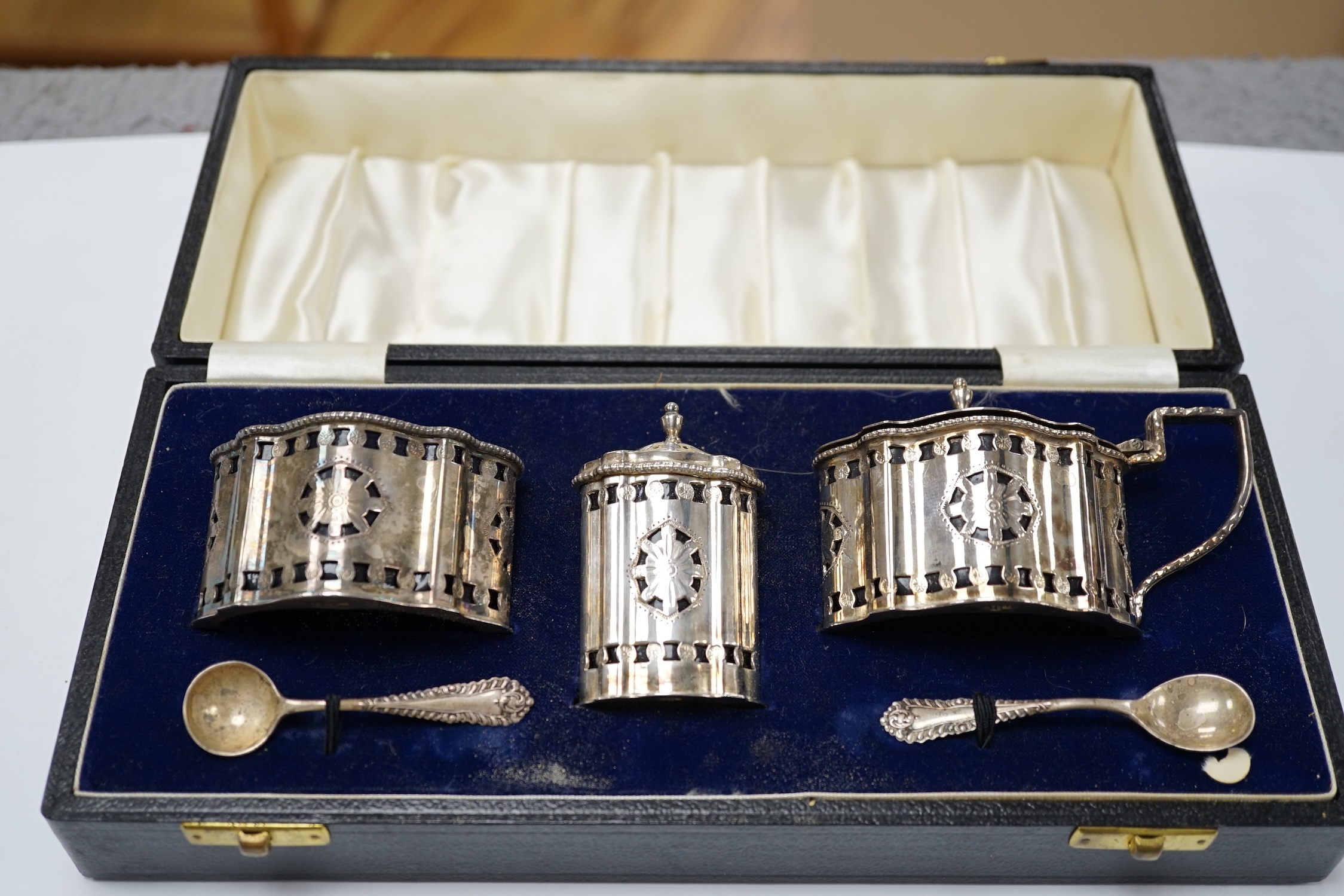 A cased 1970's silver three piece condiment set and two spoons by A. Chick & Sons, London, 1972, with blue glass liners (chipped). Condition - poor to fair